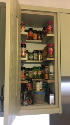 an open cabinet with spices and other food items in the bottom shelf is seen here