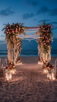 an outdoor wedding set up on the beach with candles and flower arrangements in front of it