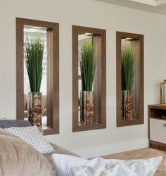 three tall vases with grass in them on the wall