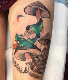 a tattoo on the leg of a woman with mushrooms and gnomes around her legs