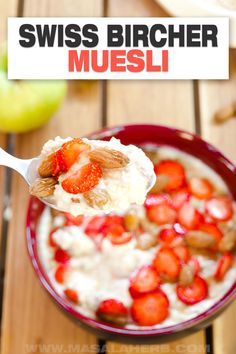 a spoon full of oatmeal with strawberries and nuts in it, on top of a wooden table