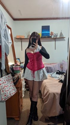 a woman taking a selfie in her bedroom wearing a pink and white corset