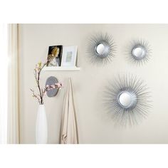 three sunburst mirrors mounted on the wall above a vase with flowers in it