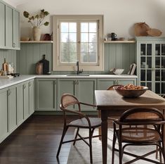 a kitchen filled with lots of green cabinets and counter top next to a wooden table