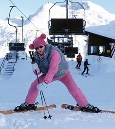 a woman riding skis down the side of a snow covered slope next to a ski lift