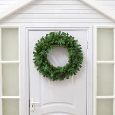 a green wreath on the front door of a white house