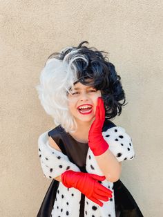 a woman with white hair wearing red gloves and polka dot dress posing for the camera