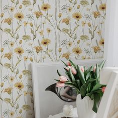 a vase filled with flowers sitting on top of a table next to a wall paper