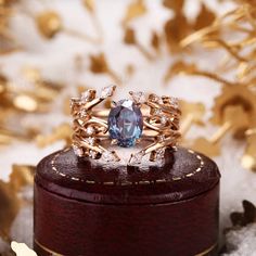 a white opal ring sitting on top of a wooden box next to gold leaves