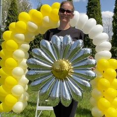 a woman standing in front of a giant balloon arch with a large flower on it