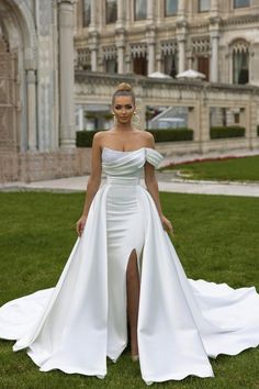 a woman in a white wedding dress standing on the grass with her legs spread out