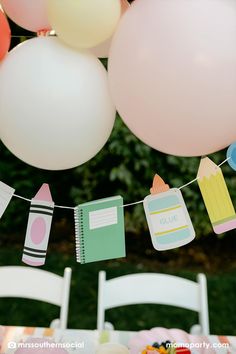 a party with balloons, paper decorations and books hanging from the line above it on a string