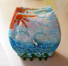 a mosaic glass vase sitting on top of a table