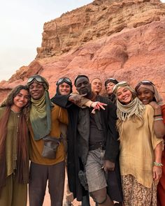 a group of people standing next to each other in front of a rocky mountain range