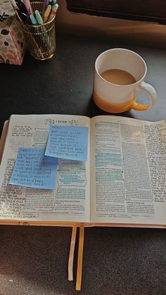 an open book sitting on top of a table next to a cup of coffee