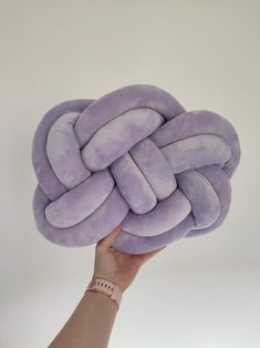 a hand holding up a purple knot pillow