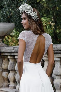 the back of a woman wearing a white wedding dress with lace and pearls on it