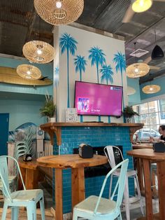 the interior of a restaurant with palm trees painted on the wall and chairs around tables