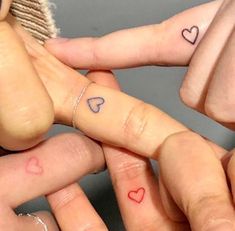 three fingers with hearts tattooed on them