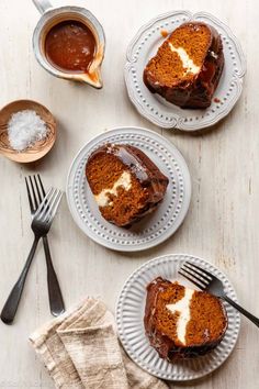 three slices of cake on plates with forks and spoons next to each other,