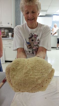 an older woman is making tortillas in the kitchen