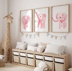 a nursery room with three pictures on the wall and two stuffed animals hanging above it