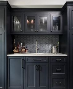 a kitchen with black cabinets and marble counter tops