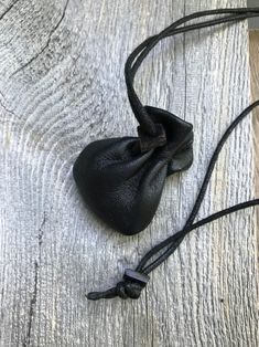 a small black bag sitting on top of a wooden table next to a string tied around it