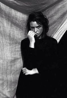 a black and white photo of a woman with her hand on her face in front of a curtain