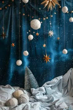 a bed with white sheets and stars hanging from the ceiling above it, next to a christmas tree