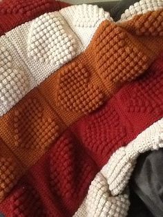 an orange and white knitted blanket laying on top of a bed