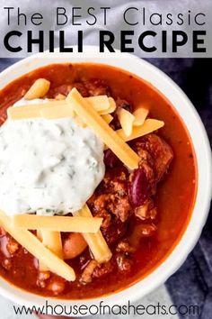 a white bowl filled with chili and cheese on top of a blue table cloth next to a