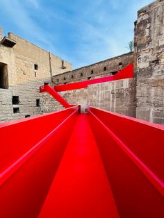 a very long red walkway in front of some brick buildings and blue sky with wispy clouds