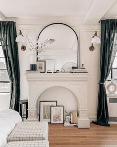 a living room filled with furniture and a fire place in front of a mirror on the wall