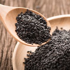 a wooden spoon filled with black seed on top of a table