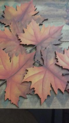 three maple leaves laying on top of a wooden table