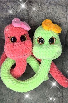 two knitted toys with eyes and hair on top of a gray blanket in the shape of an octopus