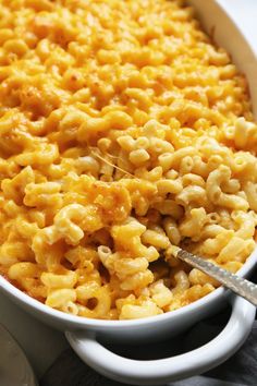 macaroni and cheese in a white casserole dish with a serving spoon