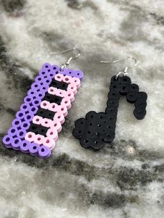 two pairs of earrings with the word bead spelled in black, pink and purple