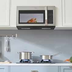 two pots and pans sit on the counter in front of an open microwave oven