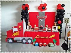 a birthday party with balloons and decorations on the table, along with a red truck