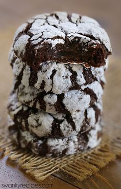 three chocolate crinkle cookies stacked on top of each other with powdered sugar