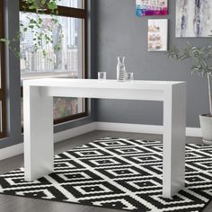 a white table sitting on top of a black and white rug next to a window