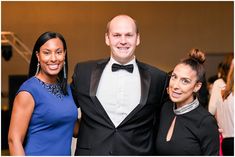 three people standing next to each other in formal wear