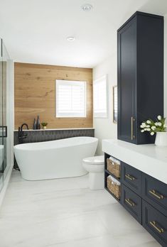 a bathroom with a large white tub next to a toilet and sink in front of a wooden wall