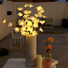 an arrangement of flowers in a vase on a table with two candles and a candle holder