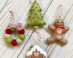 three ornaments are hanging on a white wooden surface, one has a gingerbread man and the other is a christmas tree