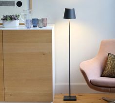 a living room with a chair and lamp on the floor next to a cabinet in front of it