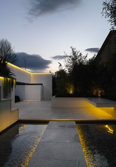 an outdoor area with water features and lights on the walls, along with concrete steps leading up to a white building