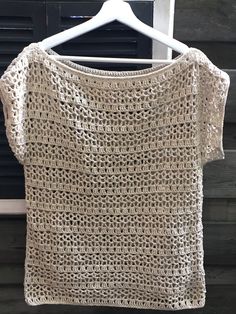 a crocheted top hanging on a hanger